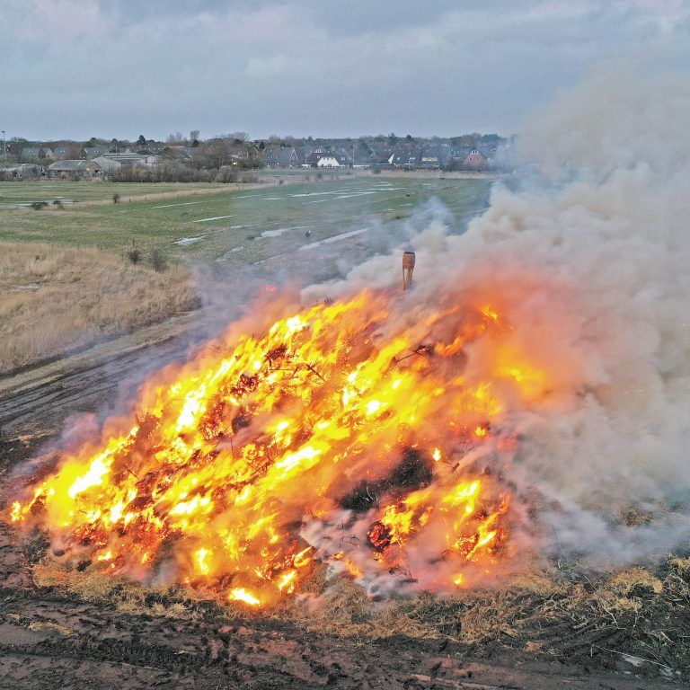 Ein großes Feuer brennt mitten auf einem Feld.